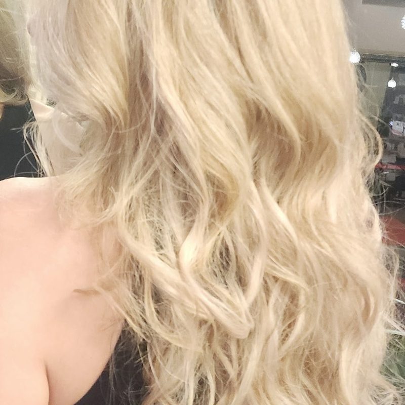 Long blonde hair extensions with soft waves, back and shoulder view